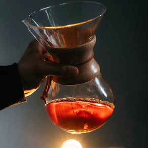 A Chemex coffee brewer in the hand of an experienced barista, showing how the perfect brew glows