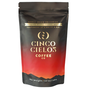 A 12 oz stand-up pouch of Cinco Cielos Coffee Co. premium Gesha coffee beans, featuring a black and red gradient design with gold lettering.