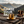 Gold mug with steam on a wooden table with mountains in the background and 'Chase Your Skies' text.