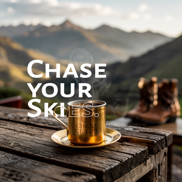 Gold mug with steam on a wooden table with mountains in the background and 'Chase Your Skies' text.